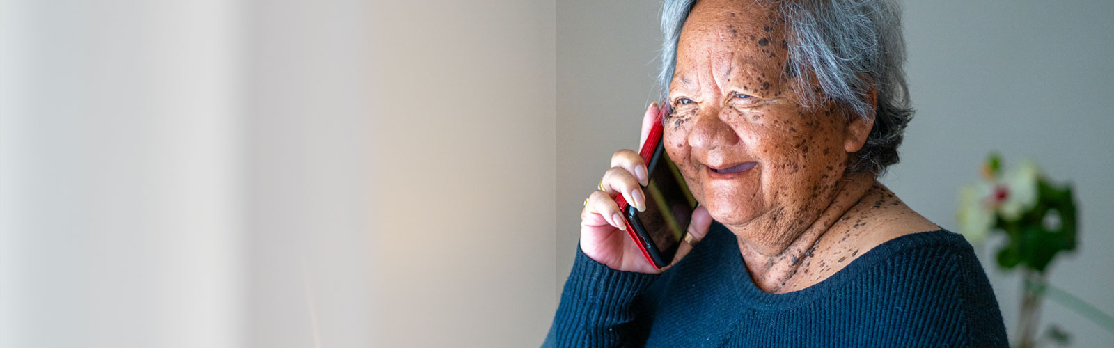 An older woman, smiling, speaking on the phone
