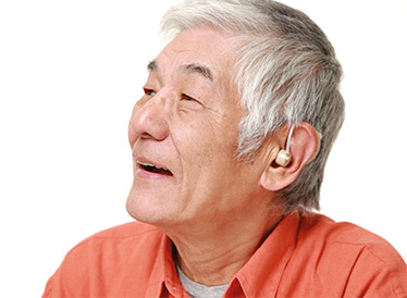 A man in an orange shirt with a hearing aid in his ear