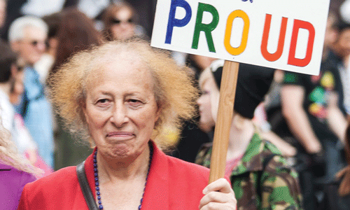 woman holding sign that says proud in colourful writing on it